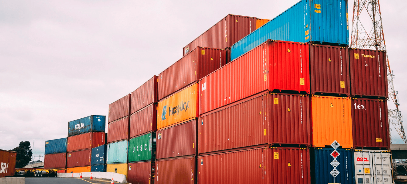 Stacked shipping containers at a cargo terminal for international freight, export, import, and global logistics operations.